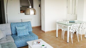 A living room with a sofa, a dining table with chairs, a pendant light, and a window with shutters. - Near sea and quiet, beautiful view   (Altea)