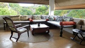 A cozy seating area with a sofa, a chair, and a coffee table, featuring a view of lush greenery outside.