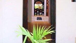 An entrance with a potted plant, wooden beams, and a hanging light fixture.