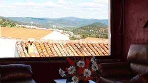 Ein Zimmer mit großem Fenster mit Blick auf eine ländliche Landschaft, einem kleinen Tisch mit Blumenvase und Ledersesseln.