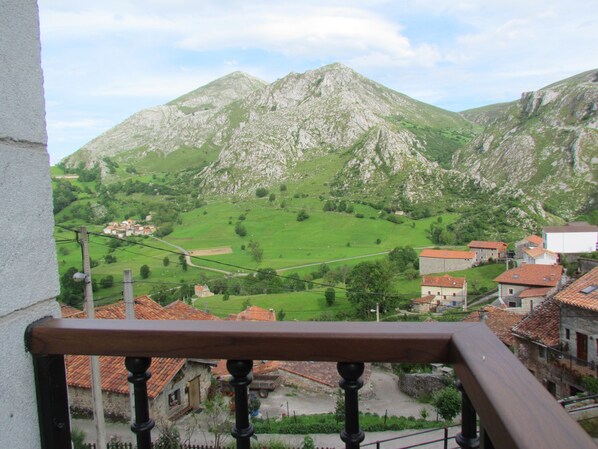 Eine gebirgige Landschaft mit einem Dorf darunter, mit traditionellen Gebäuden und roten Ziegeldächern.