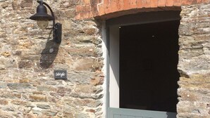 A stone building with a grey door and a black wall-mounted light fixture.