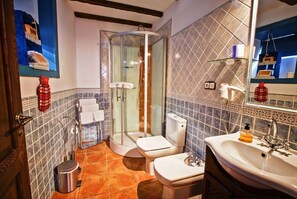 Bathroom features a glass-enclosed shower, toilet, and sink with a mirror.