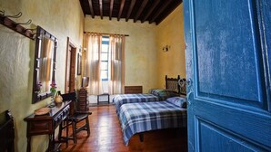 Habitació amb dos llits, mobles de fusta, un mirall i una finestra amb cortines.