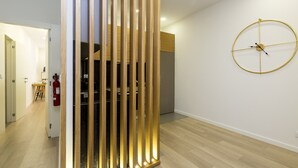 Ein modernes Interieur mit einer Holzwand, einer schlichten Wanduhr und einem sichtbaren Feuerlöscher.