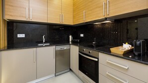 Eine moderne Küche mit Holzschränken, einer schwarzen Arbeitsplatte, einem Geschirrspüler, einem Backofen und einer Kaffeemaschine.