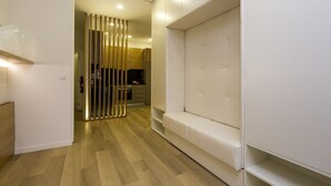 Ein modernes Interieur mit Holzboden, einem weißen Sofa und einer Küche im Hintergrund.