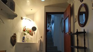 Une salle de bain équipée d’un lavabo, d’un miroir, d’une serviette et d’un escalier menant à une autre pièce.