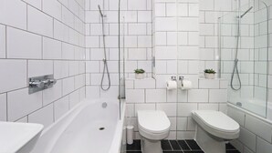 Un baño moderno con bañera, dos inodoros y zona de ducha.