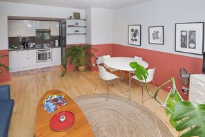 A modern kitchen with white cabinets, a dining area with a white table and chairs, and a living space with a sofa and a coffee table.