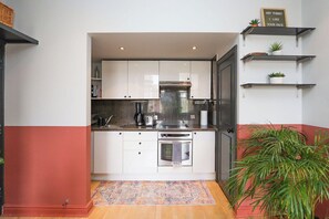 A compact kitchen with white cabinets, a built-in oven, and a coffee maker.