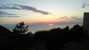 A sunset over a body of water with silhouettes of trees and a building in the foreground. - BLUE ROOM FOR RENT TWO STEPS FROM THE SEA (Ault)