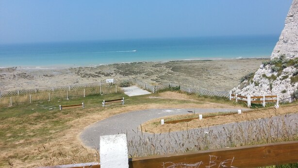 A coastal view with a sandy beach, a paved path, and a rocky cliff. - BLUE ROOM FOR RENT TWO STEPS FROM THE SEA (Ault)