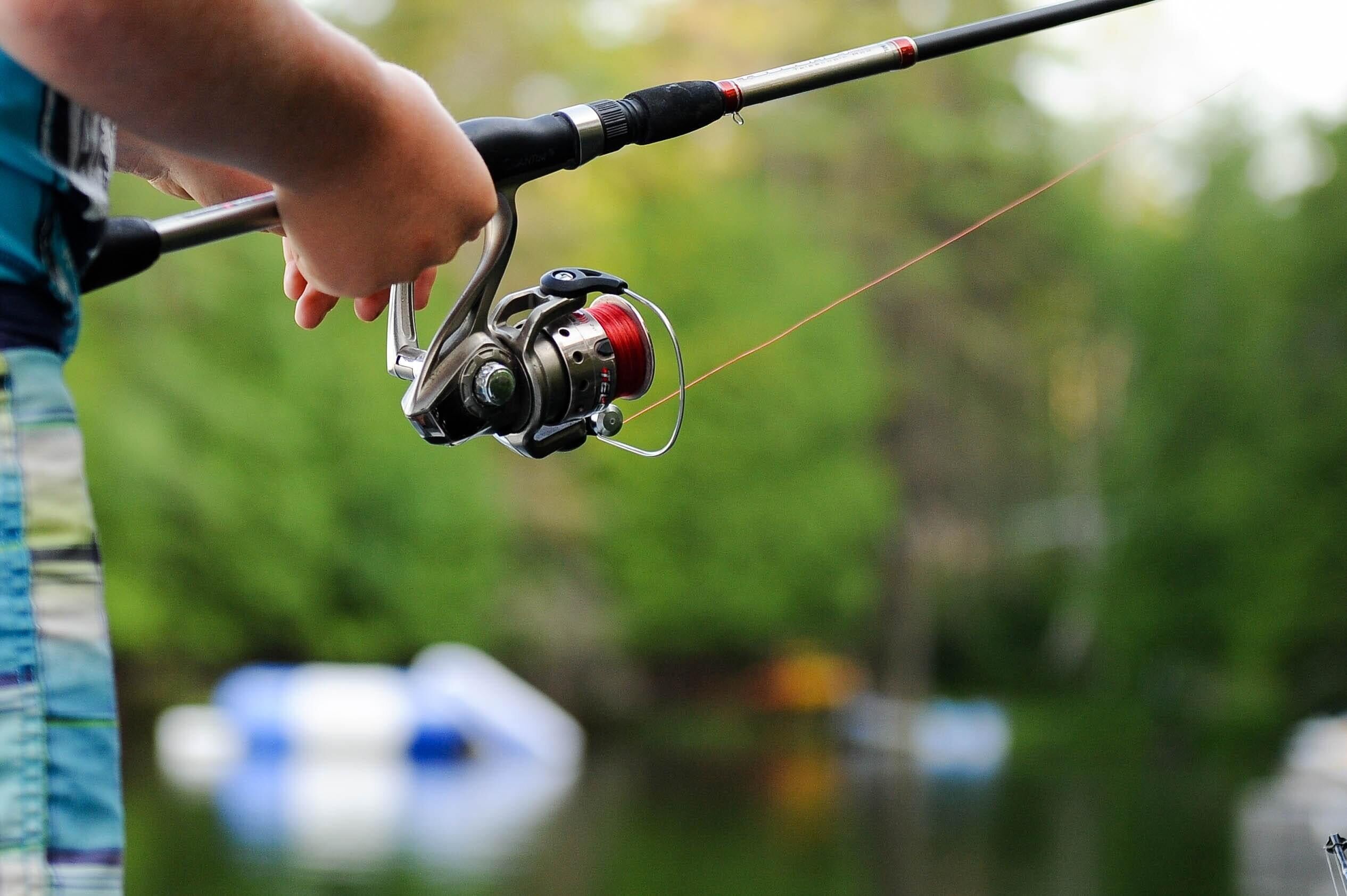 A close-up of a fishing rod with a reel, held by a person.