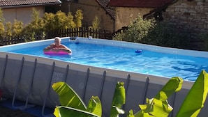 Une piscine extérieure où une personne utilise un flotteur rose.