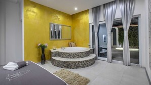 Ein modernes Badezimmer mit gelber Akzentwand, einem großen Spiegel, einer Badewanne und einer gläsernen Duschkabine.