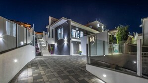 Ein modernes Gebäude mit Glasfassade, einer Treppe, die zu einer oberen Ebene führt, und einem gepflasterten Innenhof.