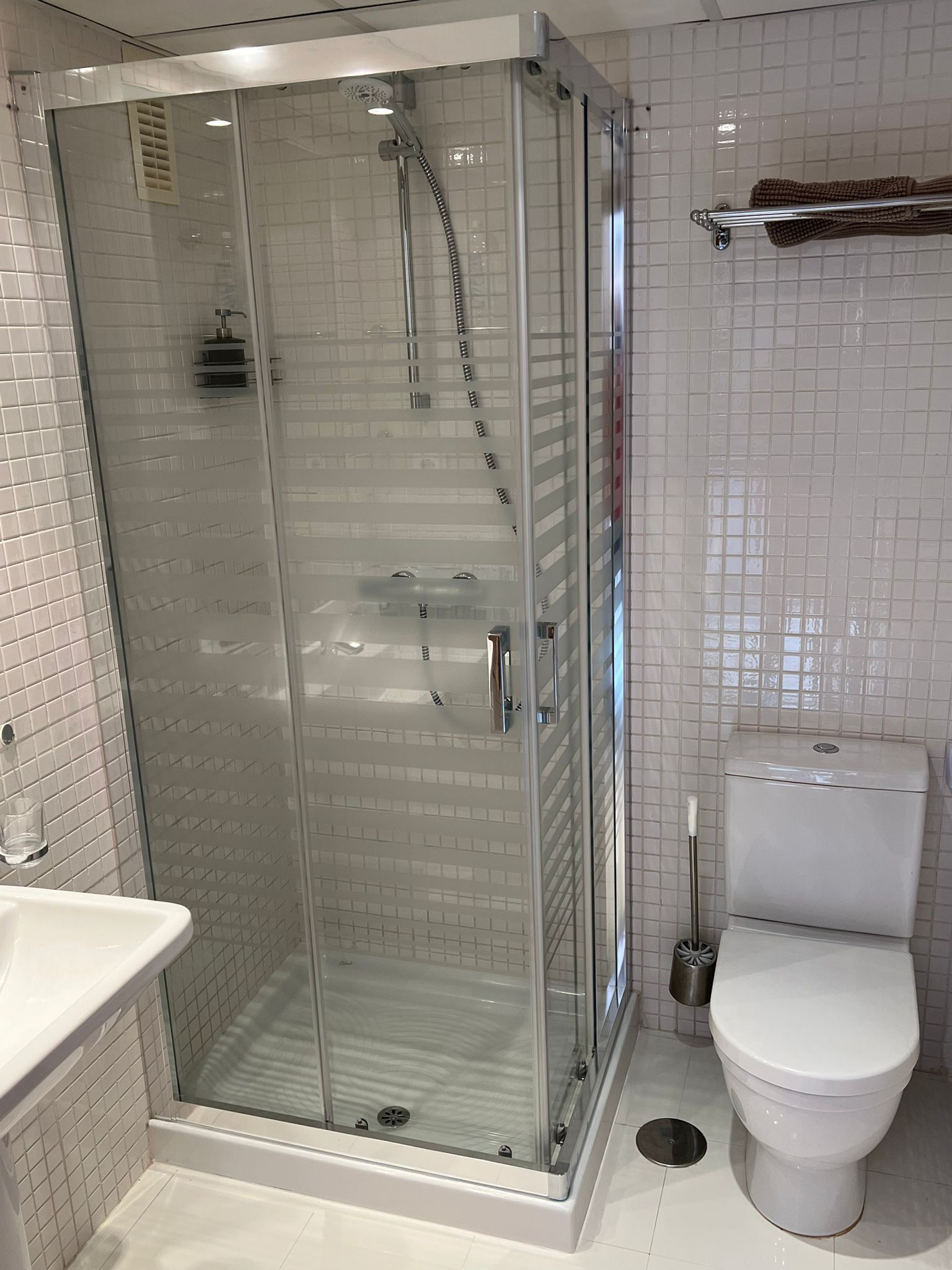 Un baño moderno con ducha de vidrio, inodoro blanco y lavamanos.