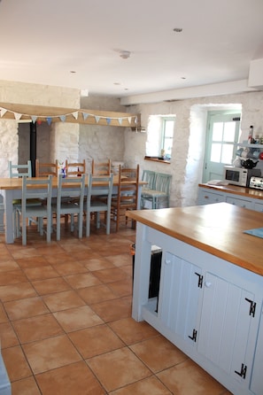 A kitchen with a wooden table and chairs, a blue cabinet, and a stone wall.