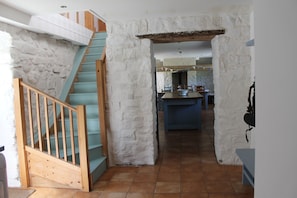 A staircase leading to a kitchen area with white stone walls and a blue countertop.