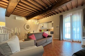 Ein Wohnzimmer mit einer Couch, einem Essbereich mit einem Tisch und einer Küche im Hintergrund.