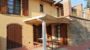 A building with a stone facade, wooden doors, and a covered patio area with tables and benches.