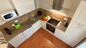 A compact kitchen with white cabinets, a microwave, a toaster, a sink, and a stove.