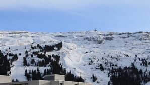 A snow-covered mountain with a ski lift and a building at the base.