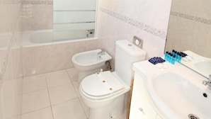 A modern bathroom with a bathtub, toilet, bidet, and sink.