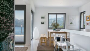A modern kitchen with a view of the sea, a chalkboard with writing, and a dining area with a table and chairs. - Beachfront Villa Poseidon with Heated Pool (Korcula)