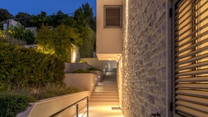 A modern building with a stone facade, a metal staircase, and a well-lit exterior. - Beachfront Villa Poseidon with Heated Pool (Korcula)