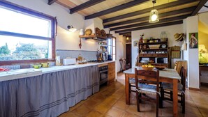 A kitchen with a large window, wooden beams, and a dining area with a wooden table and chairs. - Nice relaxing country house with private pool (Inca)