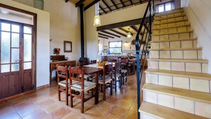 A spacious dining area with wooden tables and chairs, a staircase leading to an upper level, and a kitchen in the background. - Nice relaxing country house with private pool (Inca)