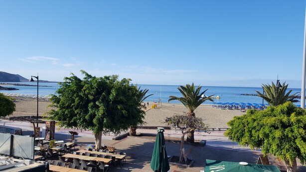Ein Restaurant direkt am Strand mit Außenbereich, Blick aufs Meer und einem Rettungsturm.