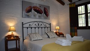 Una camera da letto con un letto, due comodini, lampade, una finestra con tende e un quadro appeso al muro.