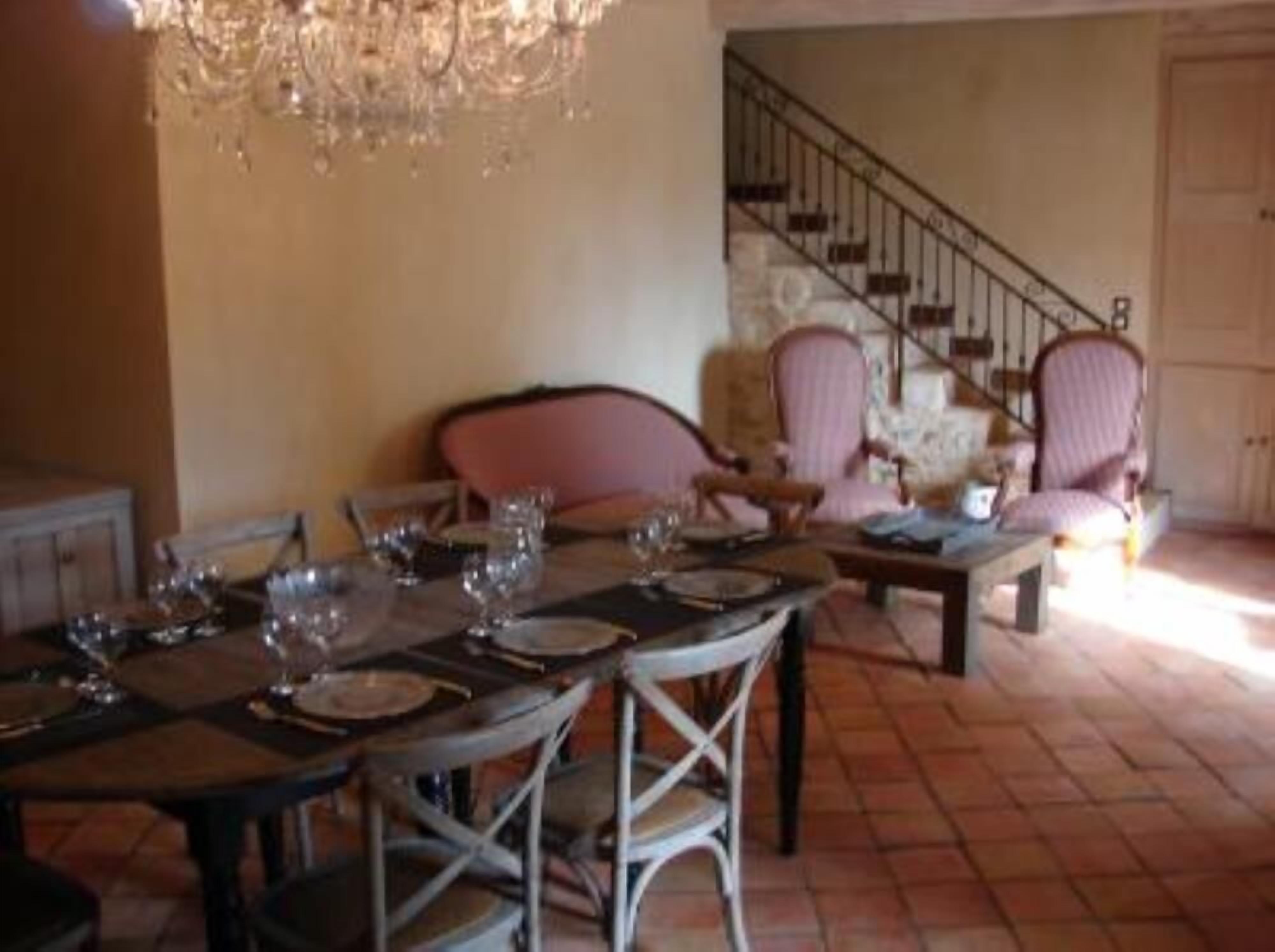 Un comedor con una mesa dispuesta para cuatro personas, una escalera y dos sillones.