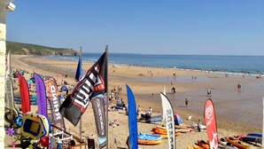 A beach with kayaks and canoes lined up, flags, and a clear view of the sea. - Family friendly cottage close to Praa Sands beach (Helston)