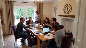 A group of people in a meeting room with laptops, a clock, and a fireplace. - Large Family Cottage With Hot Tub, Ideally Located For Activities. Pet Friendly. (Newark)