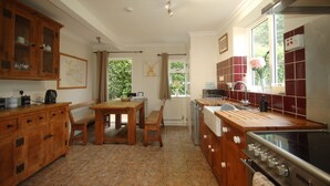 A kitchen with wooden cabinets, a dining table, and a large stove. - Large Family Cottage With Hot Tub, Ideally Located For Activities. Pet Friendly. (Newark)