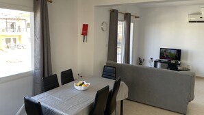 Un salon moderne comprenant un coin repas, un téléviseur et un balcon.