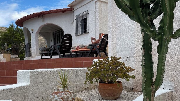 Un pati amb una taula i cadires, un cactus i una planta en test.