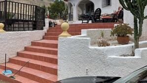 Edifici amb una escala que condueix a un pati, un cotxe al davant i un cactus en primer pla.