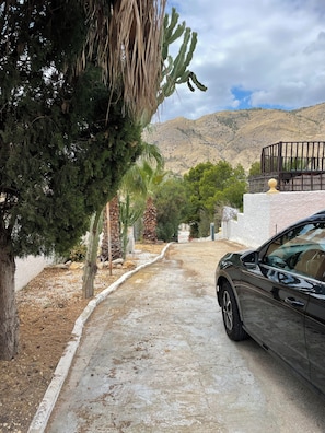 A paved driveway leading to a building with a car parked on the right.