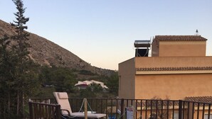 Zona de piscina amb gandules, una piscina petita i vista a un paisatge de muntanyes.