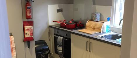 Een koelkast, een magnetron, een oven, kookgerei, borden en bestek