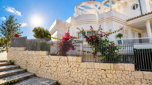 A white building with a stone wall, a metal fence, and pink flowers. - Villa in the City Center (Palma)