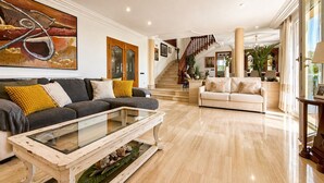 A spacious living area with a sofa, coffee table, and a staircase leading to another room. - Villa in the City Center (Palma)