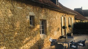 Un bâtiment en pierre doté d’une terrasse en gravier et d’un espace extérieur aménagé pour s’asseoir.
