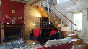 A living room with a fireplace, leather sofas, a glass coffee table, a bookshelf, and a staircase. - In the heart of the Chateaux of the Loire (Saint-Georges-sur-Cher)