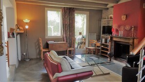 A living room with a glass coffee table, red sofa, and a fireplace. - In the heart of the Chateaux of the Loire (Saint-Georges-sur-Cher)